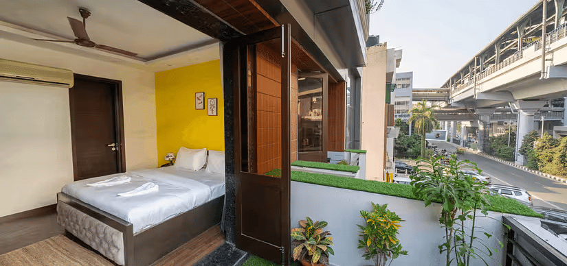 A hotel room with a balcony overlooking the metro line and urban surroundings - Lime Boutique Bed & Breakfast | Nehru Place Metro